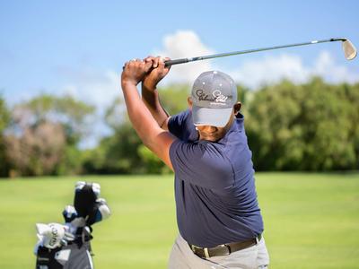 Golfista provádí švih na zeleném golfovém hřišti.