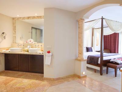 Elegancki pokój hotelowy z wolnostojącą toaletką i łóżkiem z baldachimem z ciemnoczerwonymi zasłonami.