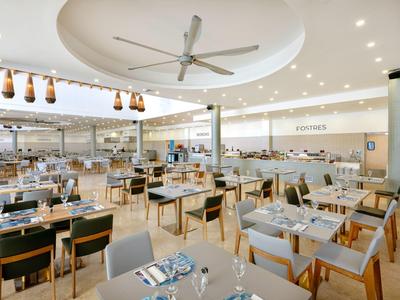 Ristorante luminoso con tavoli elegantemente apparecchiati e sedie moderne in legno.