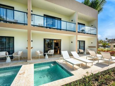 Area esterna moderna dell'hotel con piscina, lettini e balconi in una giornata di sole