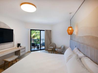 Camera d'hotel moderna con letto grande, TV, balcone e area salotto accogliente.
