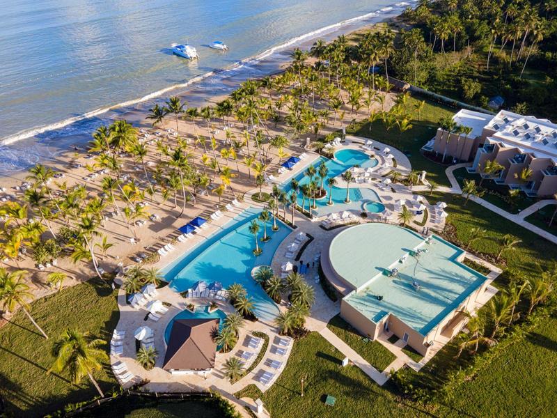 Vista aerea di un resort con piscine e spiaggia fiancheggiata da palme sul mare