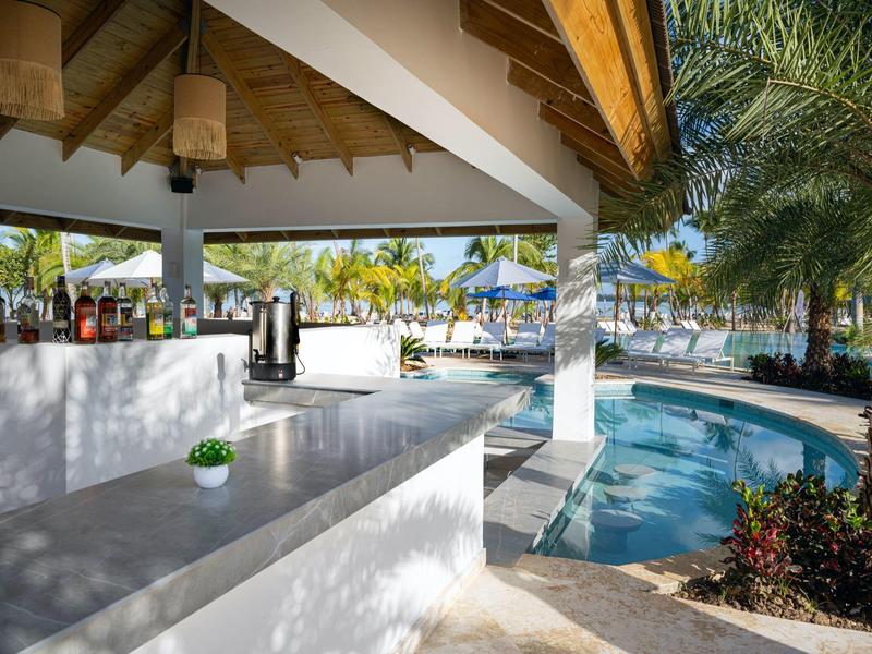 Bar aperta con piscina tropicale e palme in un resort alberghiero.