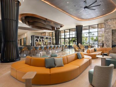 Lobby di hotel moderna con grandi finestre, sedute confortevoli e illuminazione elegante.