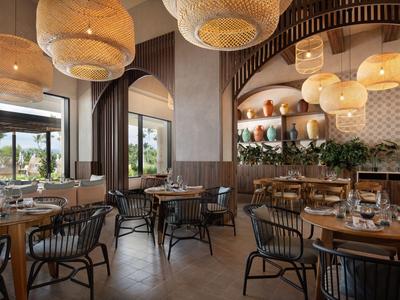 Moderner, gemütlicher Restaurantraum mit Holzmöbeln, großen Fenstern und dekorativen Lampen.