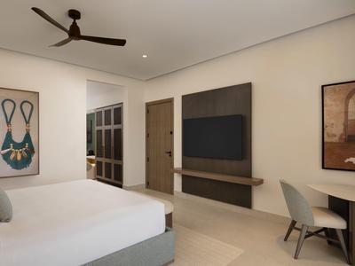 Modernes Schlafzimmer mit weißem Bett, Deckenventilator, Wand-TV und Kunstwerken an den Wänden.