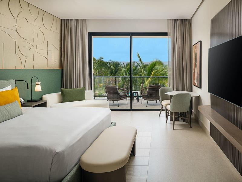 Modernes Hotelzimmer mit Doppelbett, Balkon und Blick auf Palmen