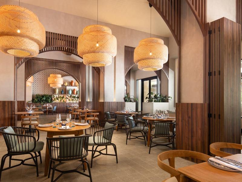 Elegantes Restaurant mit runden Holztischen, schwarzen Stühlen und großen runden Lampen