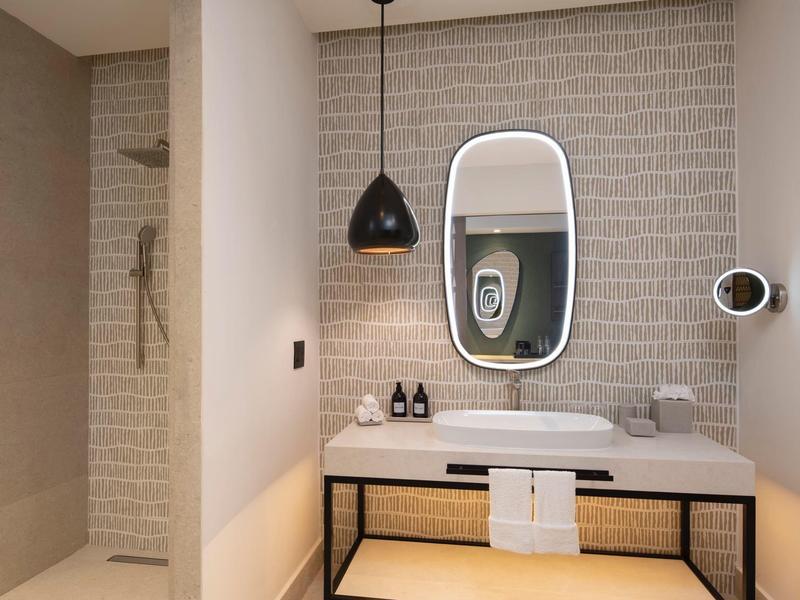 Modernes Badezimmer mit Waschbecken, Spiegel und Dusche hinter einer Glaswand