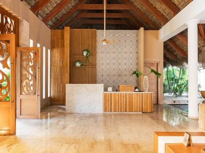 Hotel lobby with wooden accents, marble floor, decorative wall and natural light.