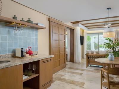 Modern kitchenette with wooden cabinets and dining area in a bright vacation rental.
