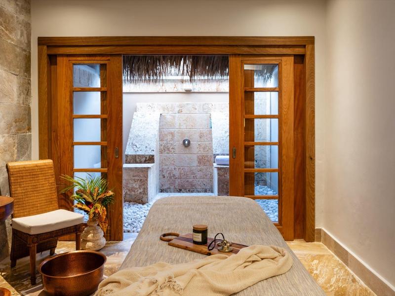 Cozy spa room with a massage table, wooden accents, and soft natural lighting.