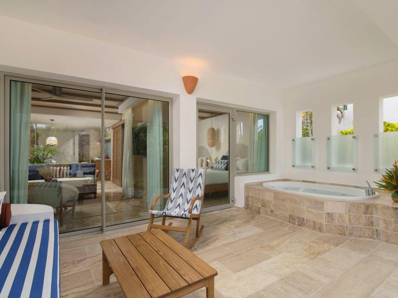 Spacious indoor seating area with wooden furniture and large jacuzzi near glass sliding doors.