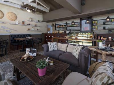 Gemütliches Café mit Holztischen, bequemen Sitzmöbeln, Pflanzen und dekorativer Wandgestaltung.