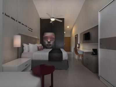 Modernes Hotelzimmer mit großem Bett, Fledermaus-Deckenventilator und Kunst am Kopfende.