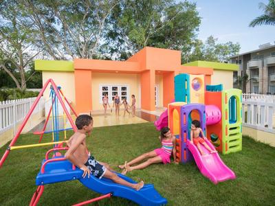 Kinder spielen auf buntem Spielplatz mit Rutsche, Schaukel und Klettergerüst im Garten.