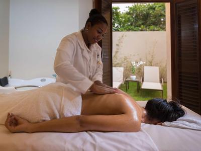 Eine Frau erhält in einem hellen Raum eine Rückenmassage auf einer weißen Liege.