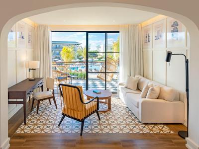 Helles Wohnzimmer mit Meerblick, Sofa, Sessel und Schreibtisch im modernen Hotelzimmer.