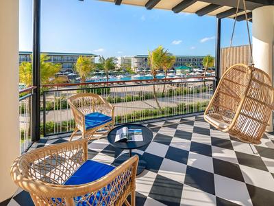 Balkon mit Rattanstühlen und Schaukel mit Blick auf Hafen und Meer