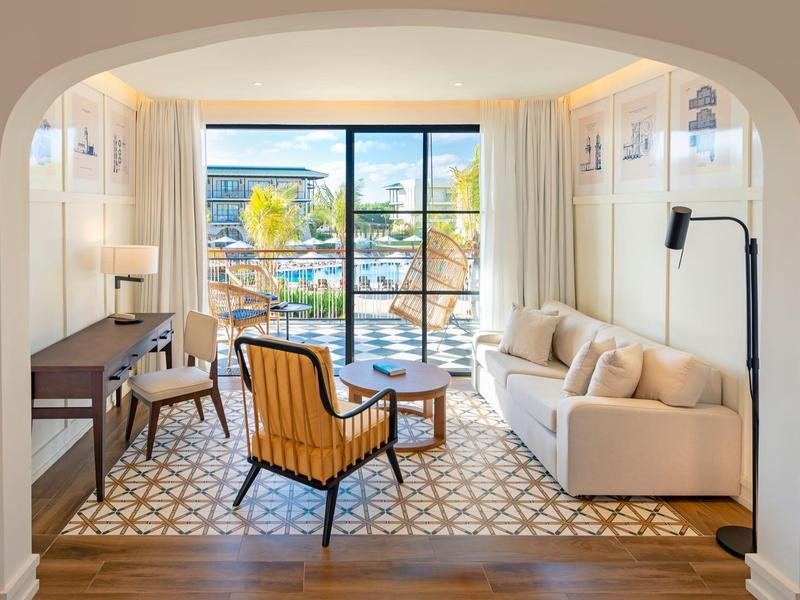 Helles Wohnzimmer mit Meerblick, Sofa, Sessel und Schreibtisch im modernen Hotelzimmer.