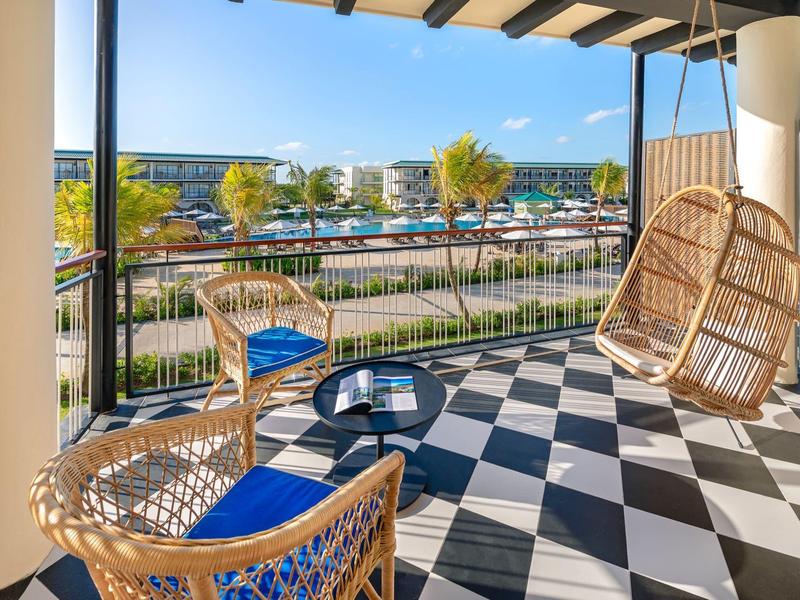 Balkon mit Rattanstühlen und Schaukel mit Blick auf Hafen und Meer