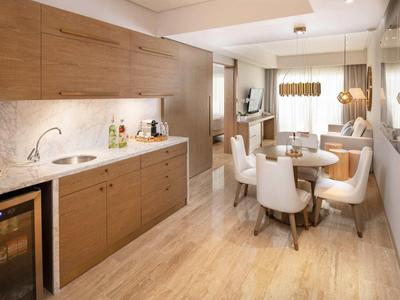 Moderne Küche mit Holzschränken, hellem Boden, rundem Esstisch und weiß gepolsterten Stühlen.