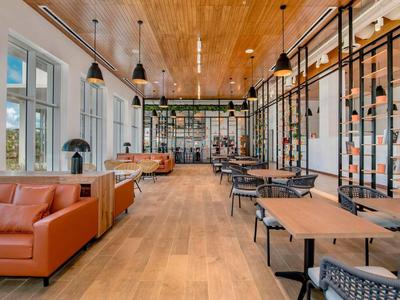 Heller, moderner Gastraum mit Holzdecke, braunen Sofas und schwarzen Metallregalen.