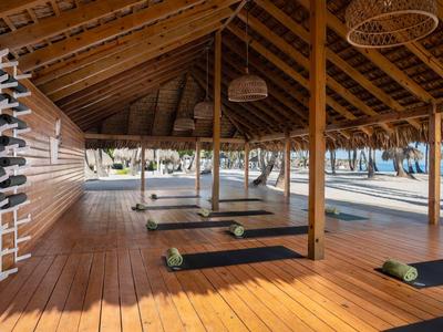 Zastřešená jógová plošina s podložkami a výhledem na palmy a pláž