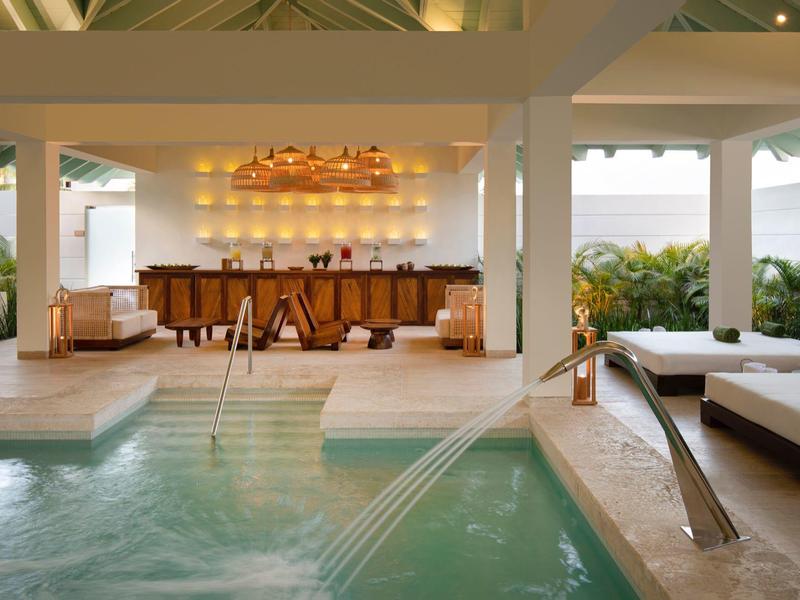 Area piscina interna moderna con lounge e bar in uno spazio luminoso e aperto.