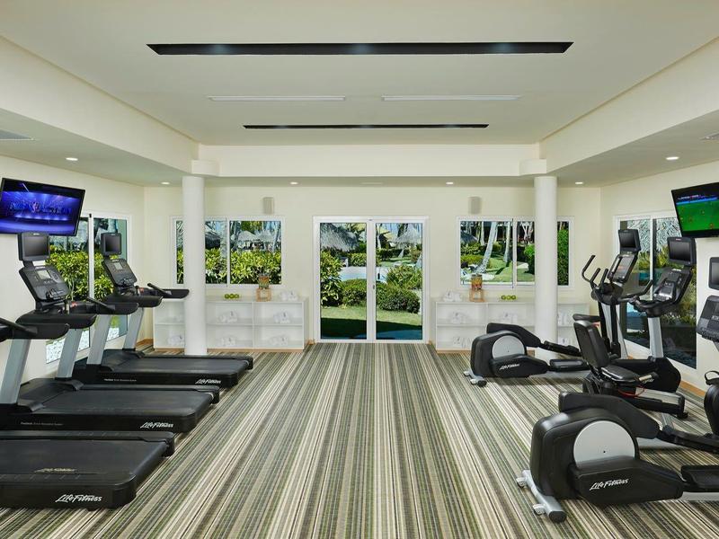 Palestra luminosa con tapis roulant, cyclette e grandi finestre con vista su aree verdi.