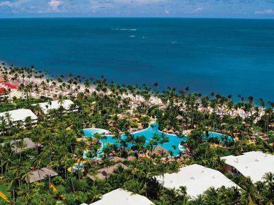 Resort di lusso con piscine e palme su una spiaggia dell'oceano blu.