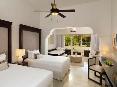 Světý hotelový pokoj se dvěma jednolůžky, stropním ventilátorem a výhledem do zahrady.