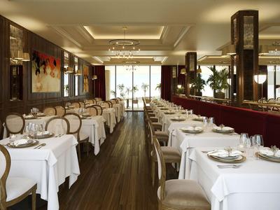 Elegantes Restaurant mit weißen Tischdecken, Holzböden und bequemen Stühlen in warmem Licht.