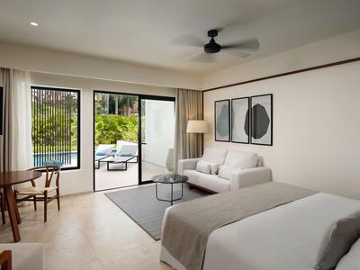 Modernes Hotelzimmer mit Bett, Sofa, Schreibtisch und Zugang zur Terrasse mit Poolblick.