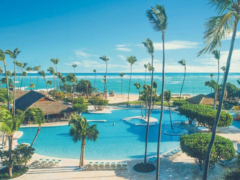 Velký bazén s palmami a výhledem na oceán za slunečného počasí.