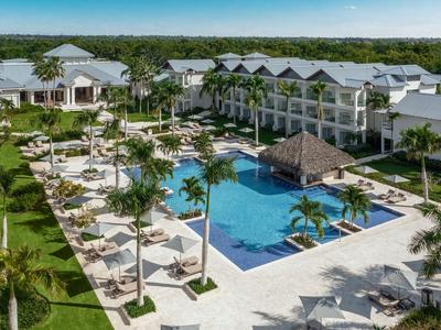 Complexe hôtelier moderne avec grande piscine, parasols et chaises longues dans un cadre tropical