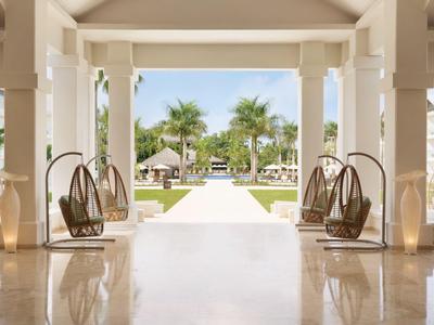 Entrée d'hôtel luxueuse avec sièges suspendus et vue sur jardin tropical et piscine.