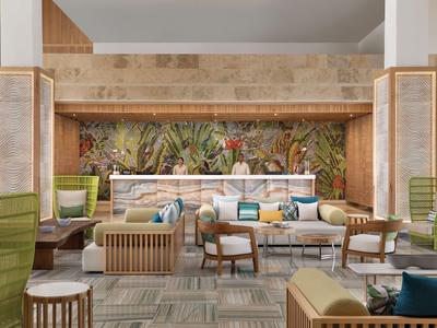 Espace lounge moderne avec canapés, fauteuils et plantes sur le mur.