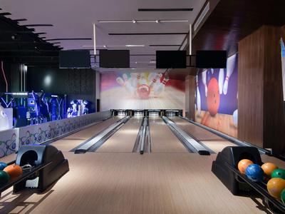Moderne Bowlingbahn mit vier Bahnen, bunten Kugeln und stimmungsvoller Beleuchtung.