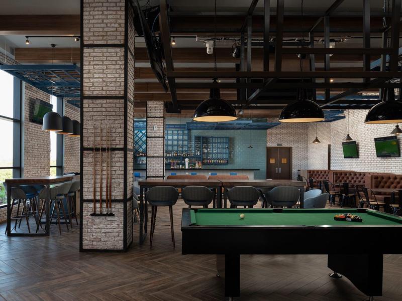 Bar moderna con mesa de billar, asientos y diseño industrial en un hotel.