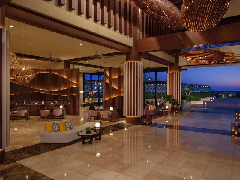 Área abierta de hotel elegante con vistas al mar y decoración moderna en tonos cálidos.