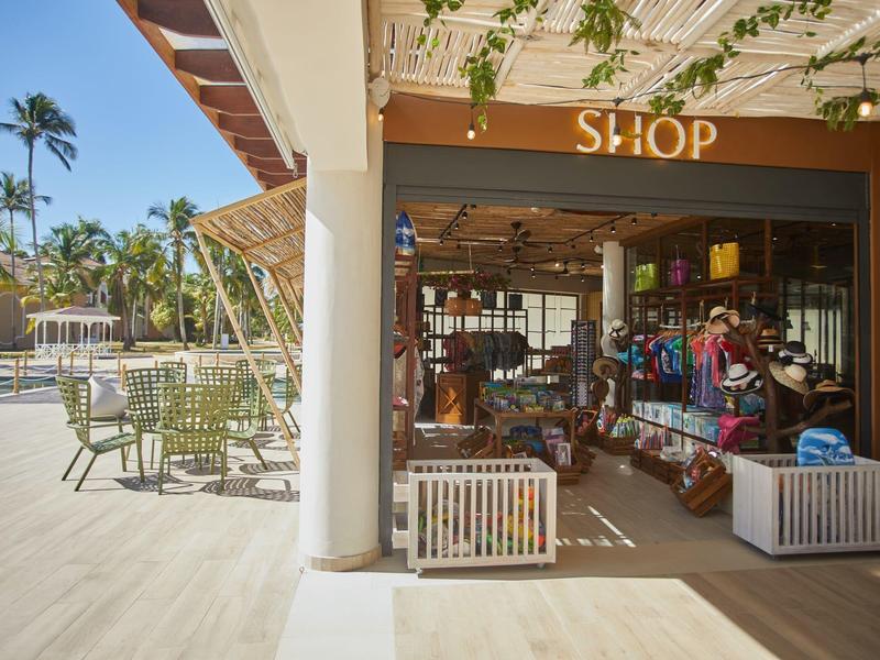 A well-lit shop with souvenirs and outdoor seating under palm trees.