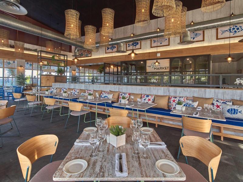 Modern restaurant area with wooden chairs, set tables, and wall decorations.