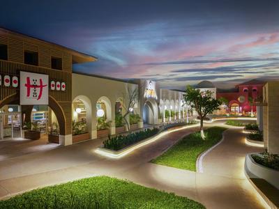 Vista di un complesso alberghiero moderno illuminato con sentieri e aree verdi al tramonto.