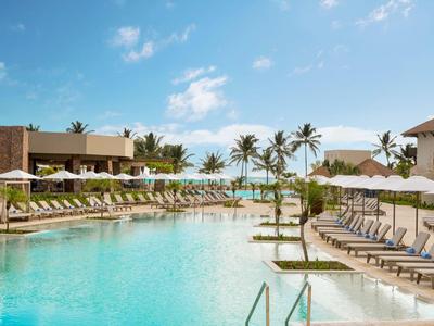 Groot zwembad met ligstoelen en parasols in een tropisch hotelresort