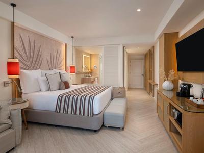 Camera d'hotel moderna con letto grande, TV, zona salotto e illuminazione d'atmosfera.