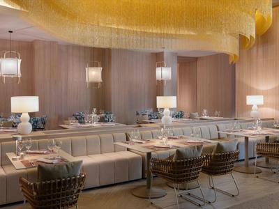 Elegantes Restaurantinterieur mit weichen Sesseln und warmem, goldfarbenem Kronleuchter.