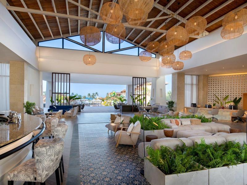 Area lobby moderna e aperta dell'hotel con posti a sedere e vista sulla piscina e il giardino.