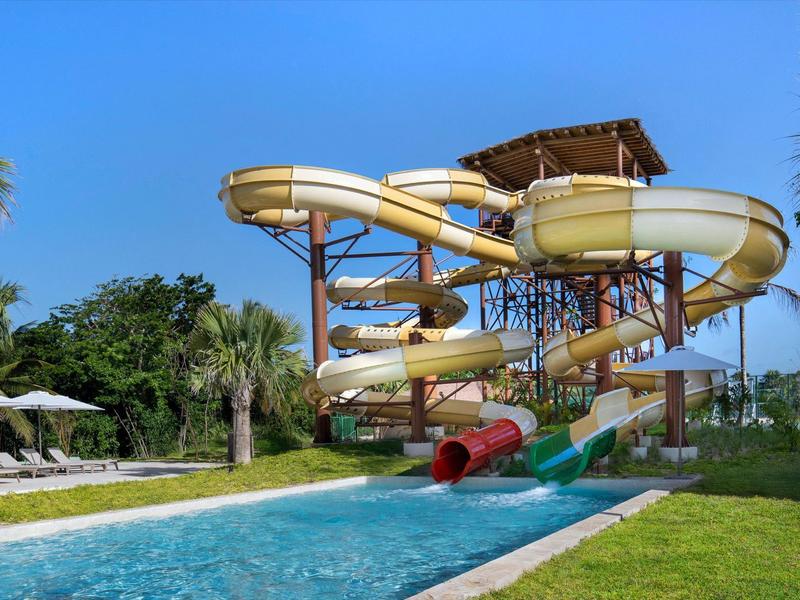 Scivoli d'acqua multipista in un'area piscina di un resort sotto un cielo azzurro.