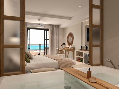 Moderně zařízený hotelový pokoj s výhledem na moře, manželskou postelí a pohodlným posezením.